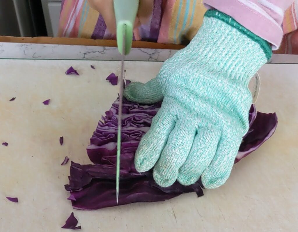 child cutting cabbage with protective glove